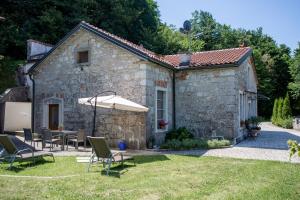 Casa de piedra con mesa, sillas y sombrilla en Villa Anton - The Old Dairy en Hrušica