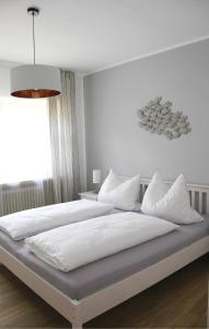 um quarto com uma cama grande com lençóis brancos e almofadas em Strandhütte em Norddeich