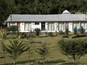 uma casa branca com árvores em frente em Lodge Guarida del Trauco em Puqueldón