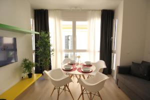 馬拉加的住宿－Apartamentos Romero Luna，客厅配有桌子和白色椅子