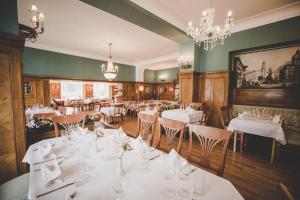 a restaurant with white tables and chairs and a chandelier at Kurhotel & Hotel Mozart in Bad Gastein +30 photos