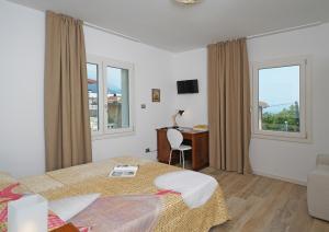 a hotel room with two beds and a desk and windows at la Luna nel Lago in Roe