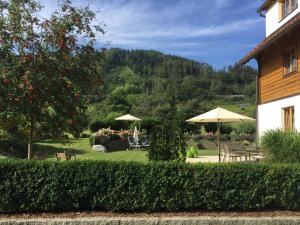 a garden with tables and umbrellas and a house at Landhaus am Bach in Übelbach