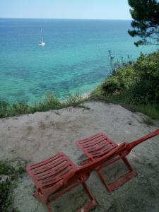 Czerwone krzesło siedzące na piasku blisko oceanu w obiekcie Ecoclub w Warnie