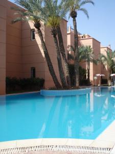 a swimming pool with palm trees in front of a building at Riad Hicham in Marrakesh