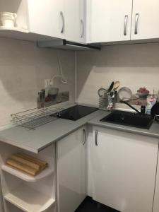 a small kitchen with white cabinets and a sink at Garsoniera Aleea Trandafirilor in Băile Herculane