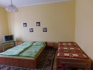 a bedroom with a bed and a tv and pictures on the wall at Bodzavirág Vendégház in Hegykő
