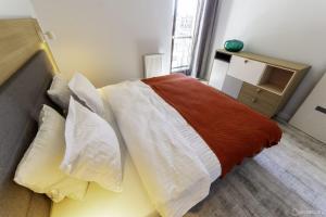 グダニスクにあるGranary Island Apartmentのベッドルーム1室(白とオレンジのシーツ、枕付)