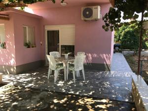 um pátio com uma mesa e cadeiras em frente a uma casa cor-de-rosa em Apartman Mirjana em Okrug Donji