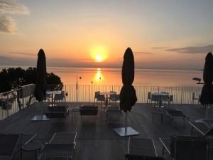 un patio con mesas y sillas y vistas a la puesta de sol en Hotel Ca' Serena, en Sirmione
