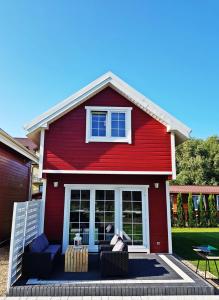 a red house with two couches and a table at Czerwone Domki in Dębki