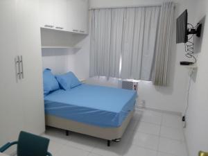 Un pequeño dormitorio con una cama azul y una ventana en Seu Cantinho, en Río de Janeiro