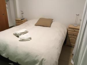 un dormitorio con una cama blanca con zapatos blancos. en Deptos Drei Kinder, en Belén de Escobar