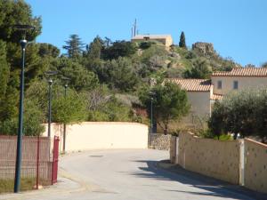 a street with a fence and a house on a hill at Leucate,dans la verdure,studio caverne en pierre dans propriété sécurisée in Leucate