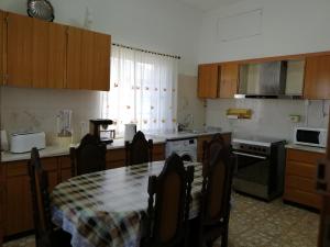 a kitchen with a table with chairs and a table and a table and a kitchen at Casa Conceição in Atalaia