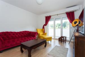 a living room with a red couch and yellow chairs at Vintage in Duće
