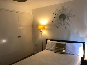 1 dormitorio con 1 cama con reloj en la pared en Spacious House 15min to Canary Wharf/O2/Excel/Central London, en Londres