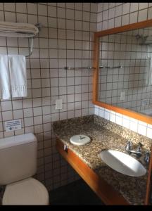 ein Badezimmer mit einem Waschbecken, einem WC und einem Spiegel in der Unterkunft Apto no IlhaFlat em frente Mar in Ilhabela