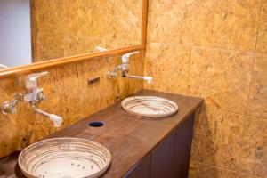 气仙沼市Guesthouse Kakehashi的浴室的木柜台上放着两个盘子