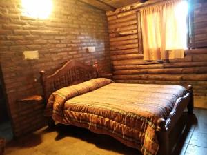 a bedroom with a bed in a log cabin at Posada la Cabaña in Villa Tulumba