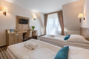 シャフラリにあるBorowy Dwór- Biznes, Spa & Funのベッド2台とデスクが備わるホテルルームです。