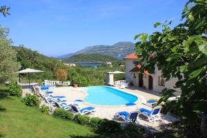 a swimming pool with lounge chairs and a house at Apartments Grgic in Korčula