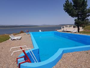 ein blauer Swimmingpool mit einer Bank und einem Stuhl in der Unterkunft Tsalka in Tsalka