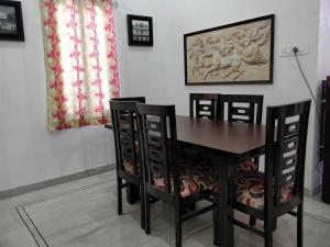 a dining room table with four chairs and a painting on the wall at Raaga Home in Udaipur