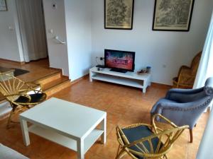 ein Wohnzimmer mit einem TV, einem Tisch und Stühlen in der Unterkunft Campillo in Berzosa del Lozoya