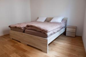 Bett in einem Zimmer mit Holzboden in der Unterkunft Family apartment near the train station in Vevey