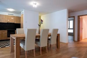 une salle à manger avec une table en bois et des chaises blanches dans l'établissement Family apartment near the train station, à Vevey