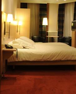 a bedroom with a bed with two chairs and two lamps at Hotel Escapade in De Haan