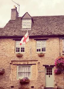uma casa com uma bandeira canadiana à sua frente em Tudor Cottage em Fairford