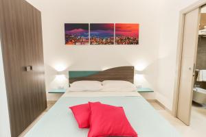 una camera da letto con un letto bianco con cuscini rossi di Cortese a Napoli