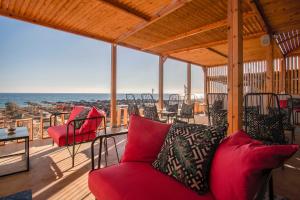 - une terrasse couverte avec mobilier rouge et vue sur l'océan dans l'établissement Armeno Resort, à Marathias