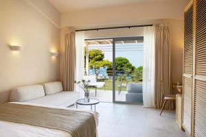 een slaapkamer met een bed en uitzicht op een patio bij ELIVI Skiathos in Koukounaries