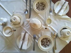 a table with white plates and silverware on a white table cloth at The Sandhill in Sandown