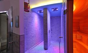 un bagno con luci viola sul muro e doccia di Villa Flora a Levico Terme