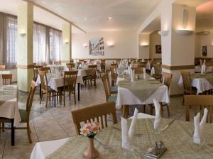 un restaurante con mesas y sillas con manteles blancos en Villa Flora en Levico Terme