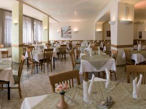 un ristorante con tavoli e sedie con tovaglie bianche di Villa Flora a Levico Terme