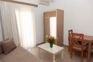 uma sala de estar com uma mesa e um vaso de flores em Sunny Suites em Máleme