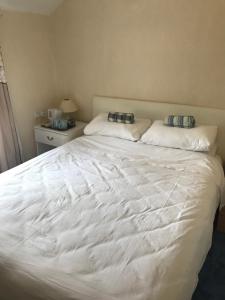 a bedroom with a large white bed with two pillows at Fern Cottage in Dorchester