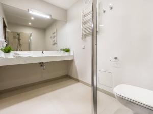 a white bathroom with a sink and a shower at VacationClub - Baltic Park Molo Apartment D110 in Świnoujście +9 photos