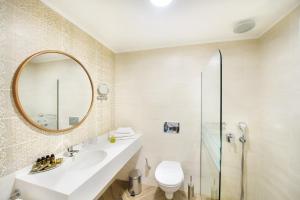 a bathroom with a sink and a toilet and a mirror at Alexandra Beach Spa Resort in Potos