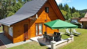uma pequena casa com uma mesa e um guarda-chuva verde em Ferienhaus Wolfs-Revier em Drognitz