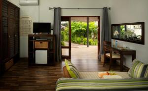 a living room with a couch and a desk and a television at Auberge Chez Plume in Anse Boileau