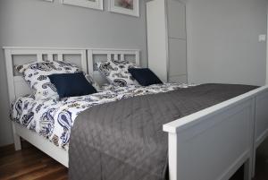 Cama blanca con sábanas y almohadas azules y blancas en Margaret Apartments, en Cracovia