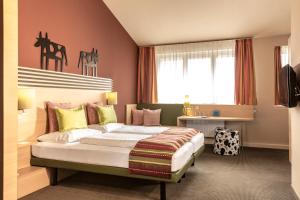 a bedroom with a bed and a desk and a window at TUI BLUE Schladming in Schladming