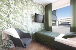 een slaapkamer met een bed, een tv en een stoel bij Hotel Milton in Jyväskylä