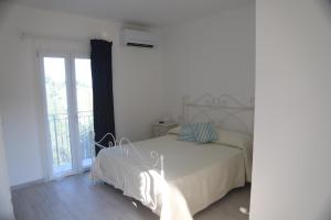 a white bedroom with a bed and a window at Il Gelso Country House in Castorano